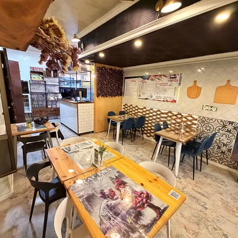 Comedor de Pizza Caravan, con mesas de madera y la carta en la pared